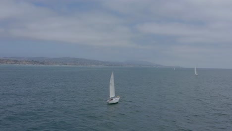 A-beautiful-aerial-drone-shot,-tracking-and-flying-around-a-sailboat-in-the-ocean,-Dana-Point---Orange-County---California