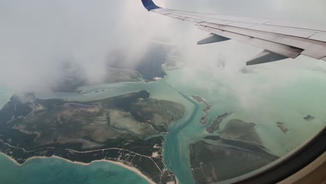 Airplane-wing-flying-above-overcast-island-of-Turks-and-Caicos-in-Caribbean