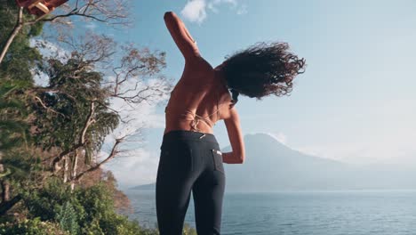 Beautiful-woman-enjoys-dancing-on-sunny-day-with-view-to-volcano-and-lake