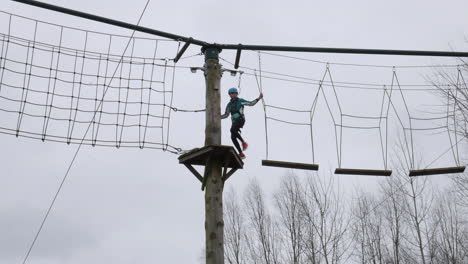 Girl-walking-across-planks-on-ropes-on-a-high-wire-adventure-obstacle-course