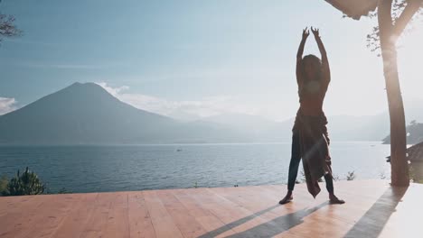 Silhouette-of-Indian-woman-dancing-on-wooden-floor-in-front-of-lake-and-Volcano