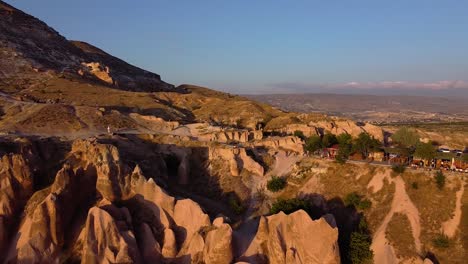 Aerial-Dolly-Enthüllt-Berg--Und-Felsformationen-Während-Des-Sonnenuntergangs-In-Der-Türkei,-Passanten-Und-Einige-Gebäude