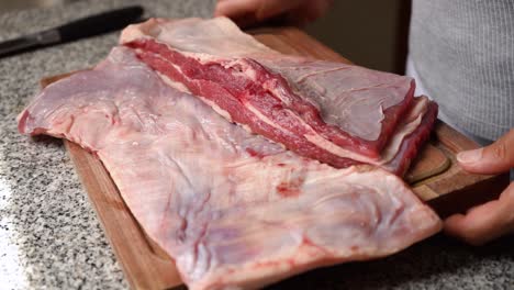 Woman-picking-up-a-cutting-board-with-freshly-cut-meat