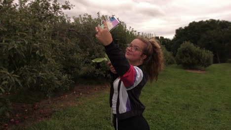 Mujer-Caucásica-Tomando-Selfie-Con-Manzana-Verde-En-La-Granja-De-Frutas-Al-Aire-Libre