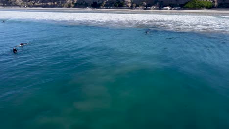 Una-Hermosa-Toma-Aérea-De-Drones,-Drones-Rastreando-Surfistas-Nadando-Hacia-El-Océano-Preparándose-Para-Una-Ola,-Carlsbad-State-Beach---California