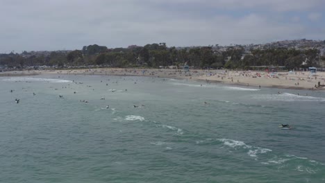 A-beautiful-aerial-drone-shot,-tracking-and-circulating-surfers-waiting-for-waves-close-to-the-beach,-Dana-Point---Orange-County---California
