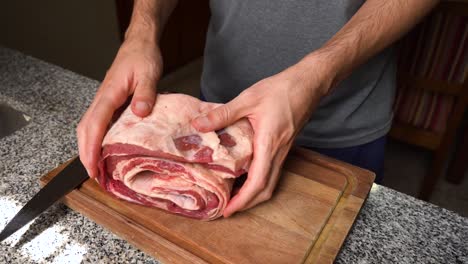 Man-rolling-up-raw-flank-meat-in-the-kitchen