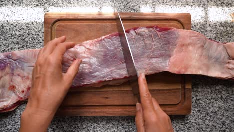 Woman-cutting-raw-flank-steak-in-half-to-cook-argentinean-"asado