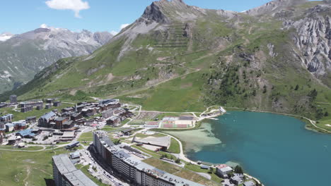 Aerial-drone-shot-panning-around-to-reveal-the-villages-which-surround-the-Tignes-ski-resort-and-the-beautiful-Lac-de-Tignes-at-the-base-of-the-Grande-Motte-glacier-in-Savoie,-France
