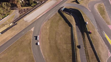 A-dynamic-aerial-shot-of-a-large-truck-while-towing-a-totalled-race-car-to-safety