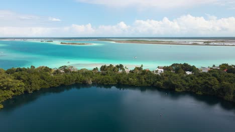 Wide-angle-panning-downward-drone-shot-showing-the-seperation-of-Cenote-Azul-and-the-famous-tourist-destination-of-the-lagoon-of-seven-colours-located-in-Bacalar,-Mexico-shot-in-4k