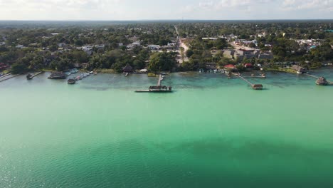 Wide-angle-establishing-drone-shot-revealing-the-beautiful-scene-of-the-lagoon-of-seven-colours-with-water-villas-located-in-Bacalar,-Mexico-in-4k