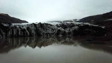 Aerial-landscape-view-of-Sólheimajökull-glacier,-melting-into-water,-in-summer,-Iceland