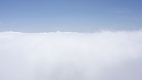 A-beautiful-drone-shot,-drone-descends-through-clouds-at-a-high-altitude,-California