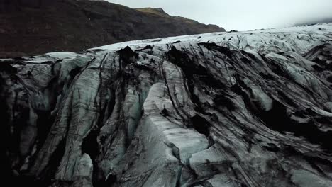 Vista-Panorámica-Aérea-Del-Hielo-Texturizado-Del-Glaciar-Sólheimajökull,-Islandia,-En-Verano