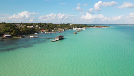 Low-approaching-a-water-villa-drone-shot-of-the-beautiful-lagoon-of-seven-colours-in-Bacalar,-Mexico-in-4k