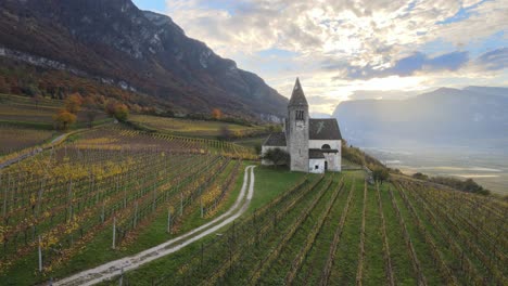 Luftdrohne-über-Einer-Mittelalterlichen-Kirche-Inmitten-Der-Weinberge-Im-Herbst-In-Südtirol
