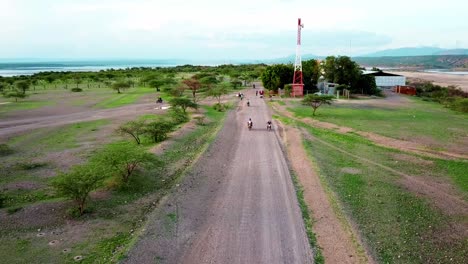 Travelers-Riding-Motorcycles-Near-Tata-Steel-Factory-Around-Lake-Magadi-In-Kenya---drone-shot