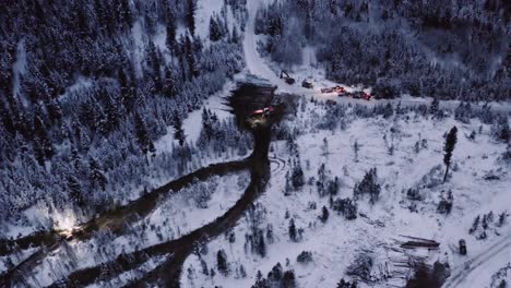 Aerial-drone-forestry-equipment-moving-in-the-winter,-at-dawn-early-morning-before-sunrise