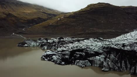 Aerial-panoramic-view-of-Sólheimajökull-glacier,-melting-into-dark-water,-in-summer,-Iceland