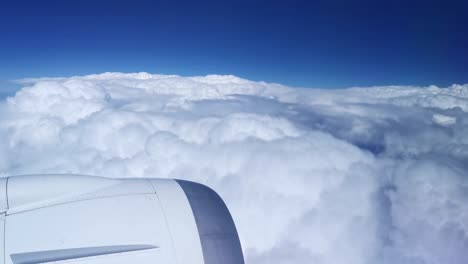 Plane-flying-over-a-thick-fluffy-cloud-cover-viewed-from-inside