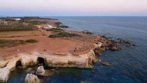 Aerial-of-sea-caves-near-Peyia,-Cyprus-during-sunset-with-blue-sea