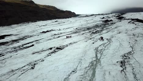 Aerial-landscape-view-of-people-walking-on-Sólheimajökull-glacier,-Iceland,-in-summer
