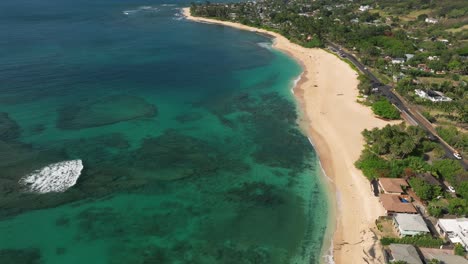 Flying-over-Hawaii-beach-with-wave-breaking-over-reef-on-a-sunny-day