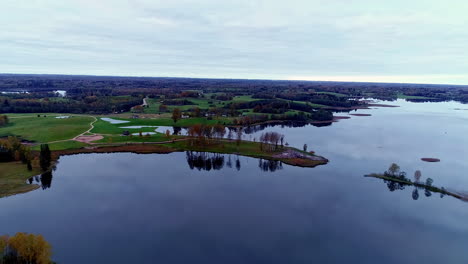 Lake-in-Baltic-states-with-clouds-reflecting-in-water,-aerial-pullback-drone-shot-4k