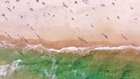 Drone-aerial-top-view-of-people-walking-along-the-famous-Bondi-Beach-in-Sydney,-Australia