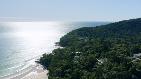 Aerial-Drone-Of-Noosa-Heads-Forest-Headland-With-Bright-Sunlight-Reflecting-Off-Ocean,-4K