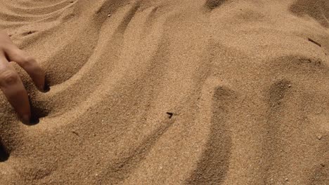 Eine-Hand,-Die-Sandmuster-An-Einem-Strand-Macht