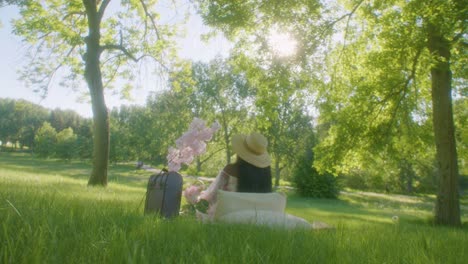 Black-lady-on-picnic-under-green-trees-in-sunny-park-points-at-something-above