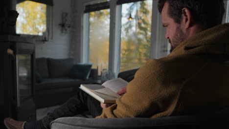 Caucasian-man-reading-a-book-in-a-warm-cottage-in-the-woods