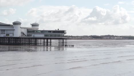 Last-section-of-the-Grand-Pier-Weston-Super-Mare-with-a-cloudy-and-blue-sky-in-the-background,-gentle-waves-crushing-in-the-beach