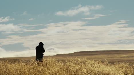 silhouette-medium-shot-of-a-photograph-standing-in-a-field-in-iceland-in-a-clear-summer-day