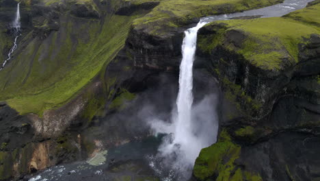 Static-aerial-shot-of-the-incredible-Haifoss-waterfall-in-the-mountain-gorge-of-Fossárdalur,-in-Iceland