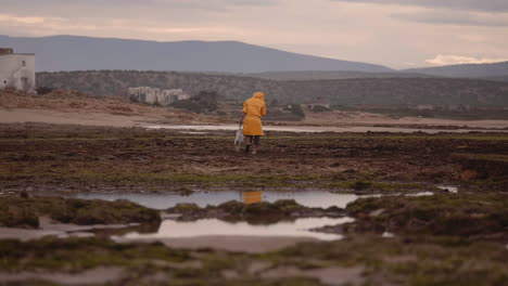 Old-fisherman-in-raincoats-walking-away,-wide-establishing-shot