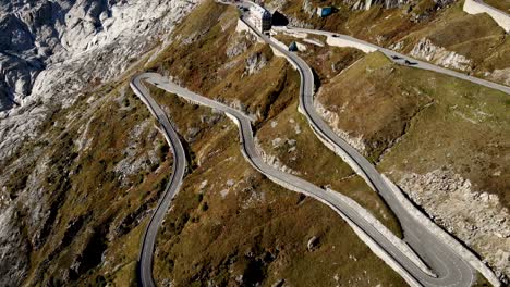 Aerial-flyover-over-Furka-mountain-pass-at-the-border-of-Valais-and-Uri-in-Switzerland-with-a-pan-up-view-from-the-curvy-road-up-to-the-Rhone-glacier-on-a-summer-day