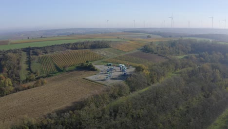 Ölpumpen-In-Der-Nähe-Von-Ackerland-Mit-Windkraftanlagen-Im-Nebligen-Hintergrund