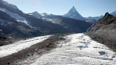 Aerial-flyover-over-the-moraines-and-crevasses-of-the-Gorner-glacier-with-the-Matterhorn-in-the-background-on-a-sunny-summer-day-in-Zermatt,-Switzerland