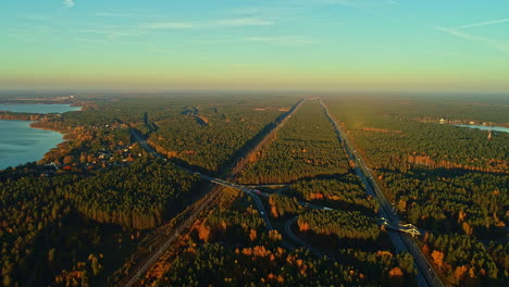 Aerial-View-Over-Scene-Forest-Landscape-With-Highway-Cutting-Through-In-Riga,-Latvia-During-Sunset