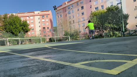 Showing-two-people-playing-tennis-on-Public-tennis-courts-filmed-in-summer-sunny-day-surrounded-by-residential-houses-and-beach-in-Portugal