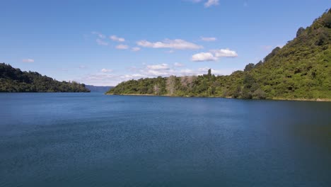 Low-fly-over-of-picturesque,-blue-Lake-Tarawera,-New-Zealand-underneath-clear-sky