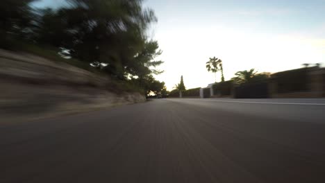POV-View-From-Rear-Car-Speeding-Along-Road-During-Sunset,-Low-Angle-Perspective