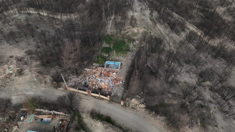 Aerial-view-orbiting-burnt-remains-of-family-homes-devastation-after-forest-wildfire
