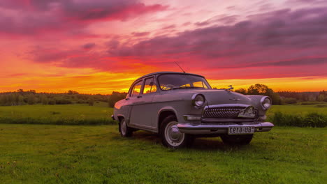 Retro-car-Gaz-21-manufactured-by-Volga-company-in-the-Soviet-Union,-standing-on-a-green-field-with-a-colorful-background-of-floating-clouds