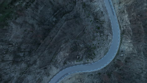 Top-down-View-Of-Winding-Road-Between-Burnt-Forest-Area-In-El-Pont-de-Vilomara,-Spain---drone-shot