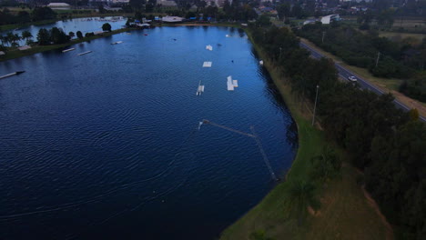 Aerial-drone-shot-of-splashing-water-from-a-ski-being-dragged-on-lake