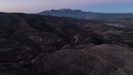 Majestic-aerial-shot-of-vast-burnt-area-with-Montserrat-mountain-at-blue-hour